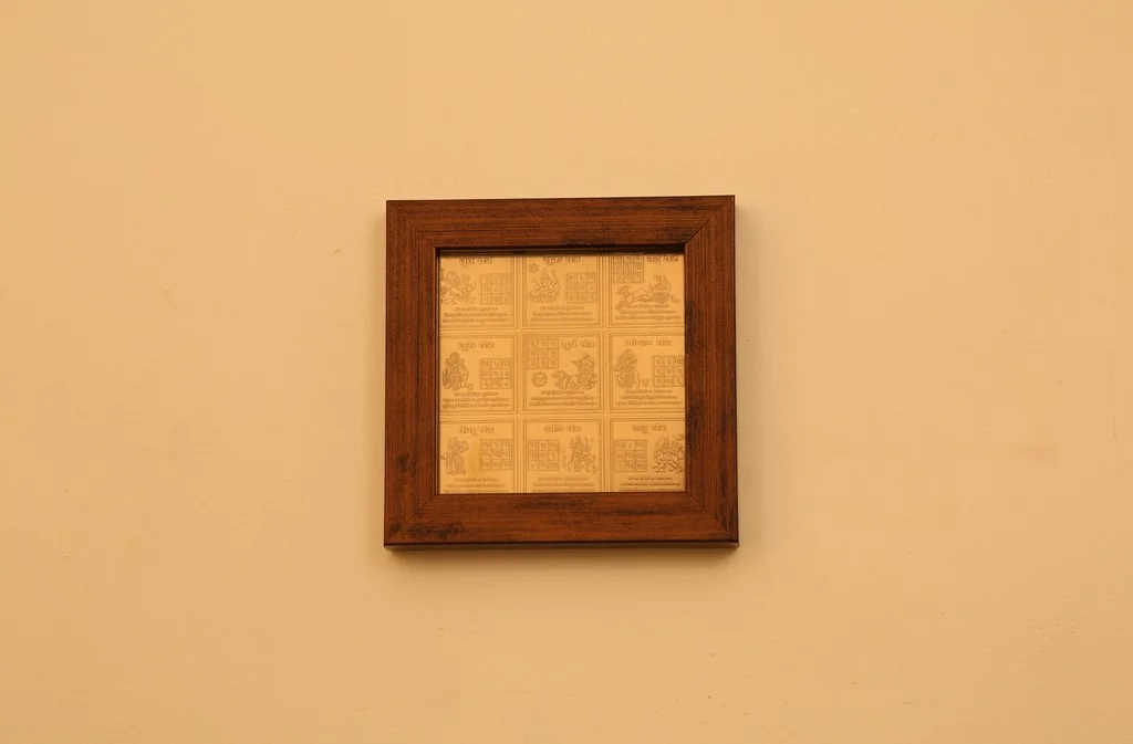 Framed Vastu yantra grid with multiple sacred symbols hanging on a beige wall