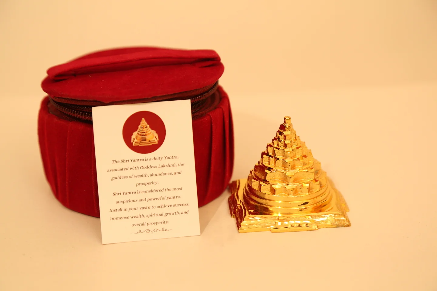 Golden Sri Yantra pyramid with red velvet storage case and information card displayed on a light background