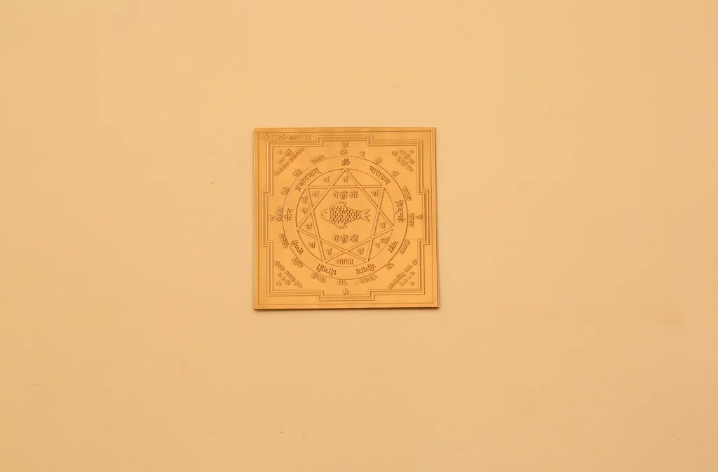 Golden Vastu fish yantra with sacred symbols engraved on a beige wall